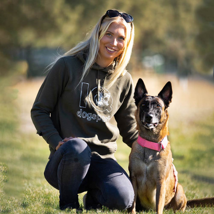 Hundeführerin belohnt Malinois mit magnetischer Hundetrainings-Tasche während der Unterordnung