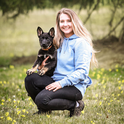 Hundeführerin in blauem Trainings-Hoodie mit Working Dog im Freien